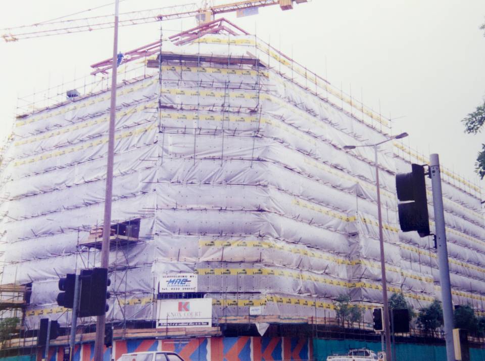 An archive MAC Scaffolding contract: a Cardiff office block sheeted to its peak under a tower crane, MAC's own site board on the hoarding