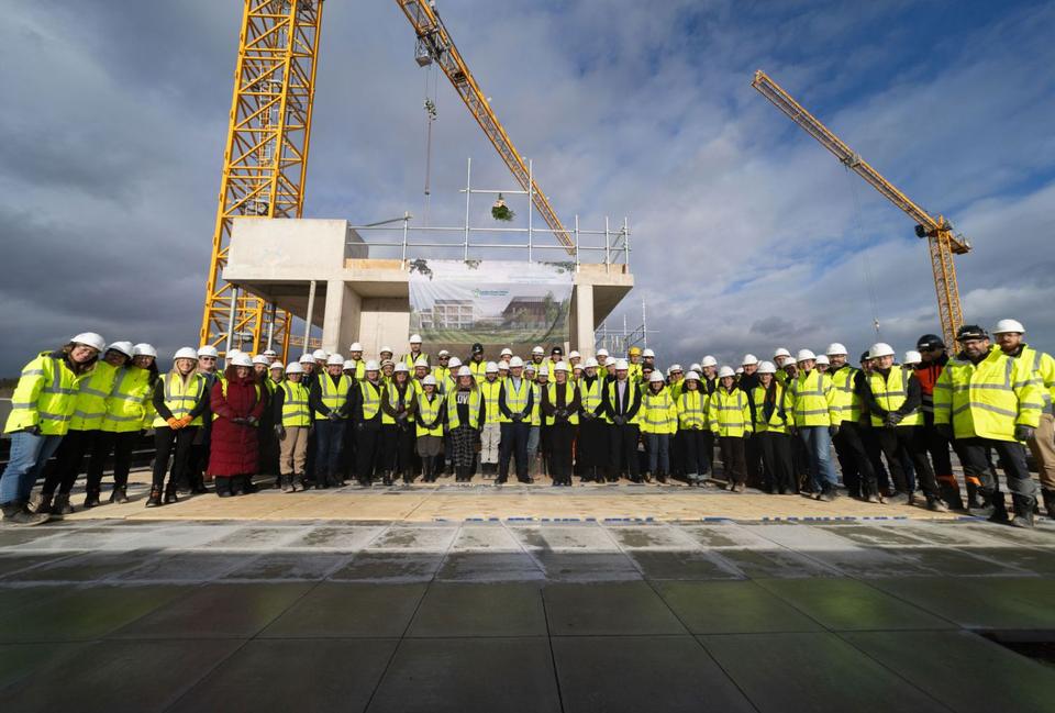 Hundreds of site workers gathered beneath the cranes for the Velindre topping-out ceremony